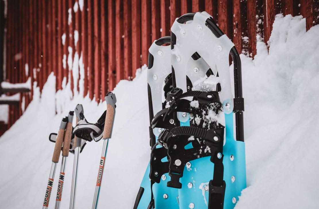 Lumikengät ja sauvat hangessa